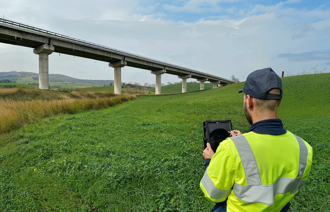 Tecnico con tablet durante l'ispezione di un viadotto